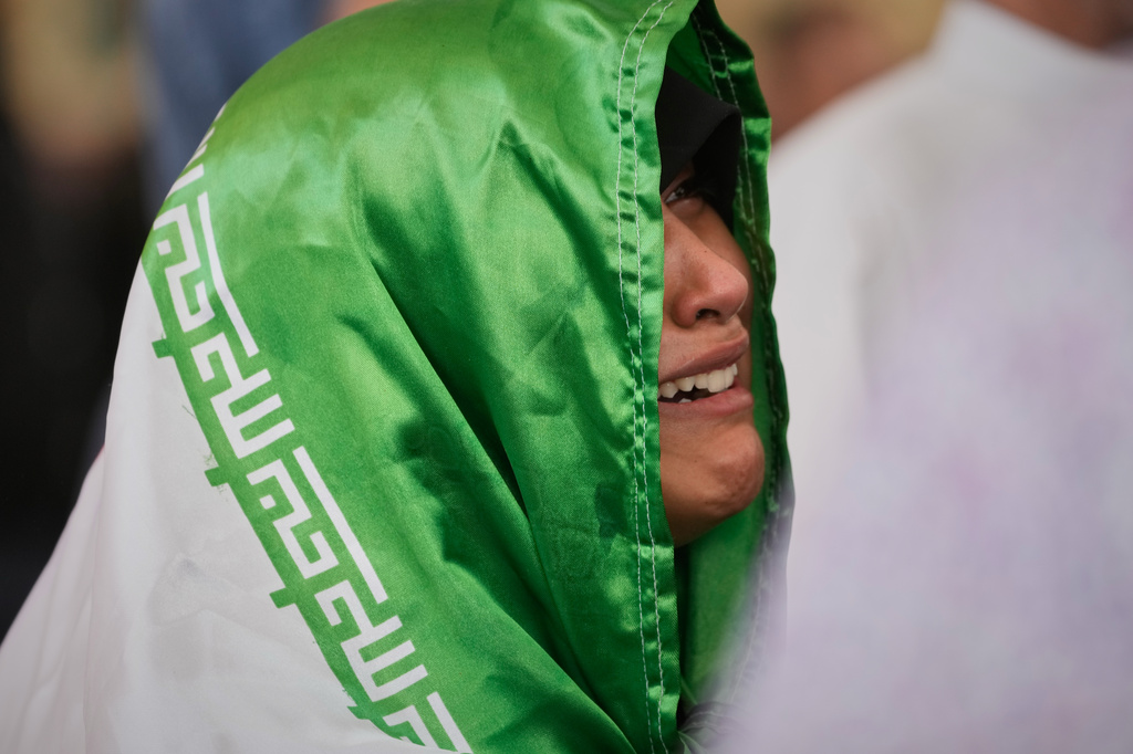 A mourner, draped in an Iranian flag, reacts during funeral prayers for the late Iranian Supreme Leader Ayatollah Ali Khamenei at the Imam Ali Shrine in Najaf, Iraq, Wednesday, July 8, 2026. (AP Photo/Hadi Mizban)