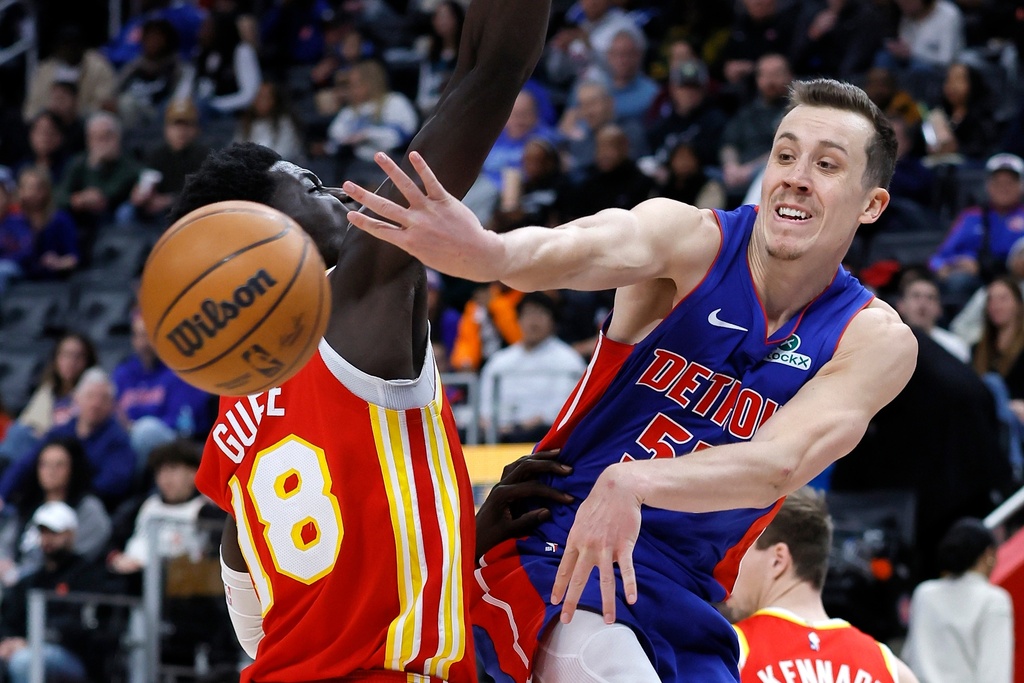 Detroit Pistons forward Duncan Robinson, right, passes the ball past Atlanta Hawks forward Mouhamed Gueye, left, during the second half of an NBA basketball game Friday, Dec. 12, 2025, in Detroit. (AP Photo/Duane Burleson)