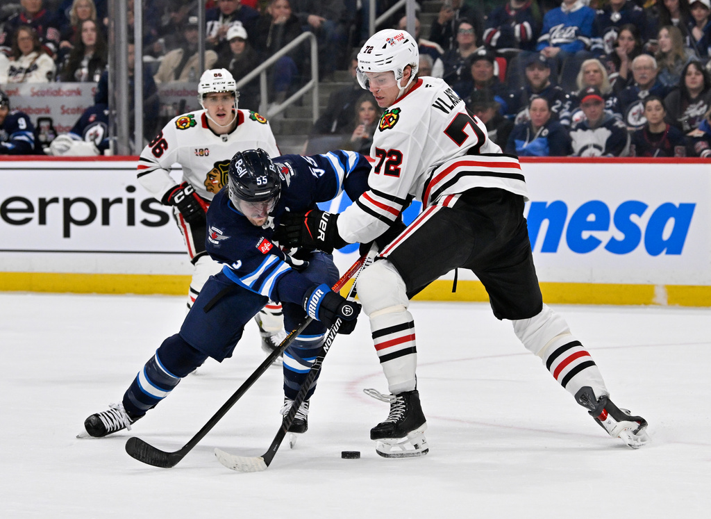 Chicago Blackhawks' Alex Vlasic (72) checks Winnipeg Jets' Mark Scheifele (55) during the second period of their NHL hockey game in Winnipeg, Tuesday March 3, 2026. (Fred Greenslade/The Canadian Press via AP)