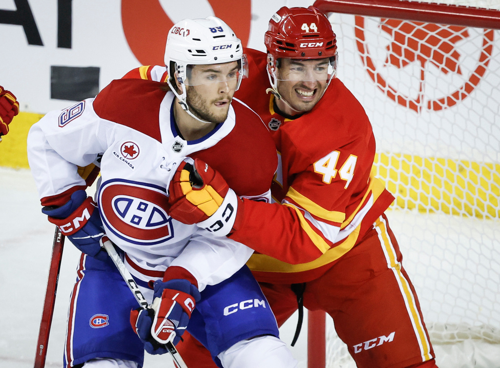 Montreal Canadiens' Joshua Roy, left, is checked by Calgary Flames' Joel Hanley during the first period of an NHL hockey game in Calgary, Alberta, on Wednesday, Oct. 22, 2025. (Jeff McIntosh/The Canadian Press via AP)