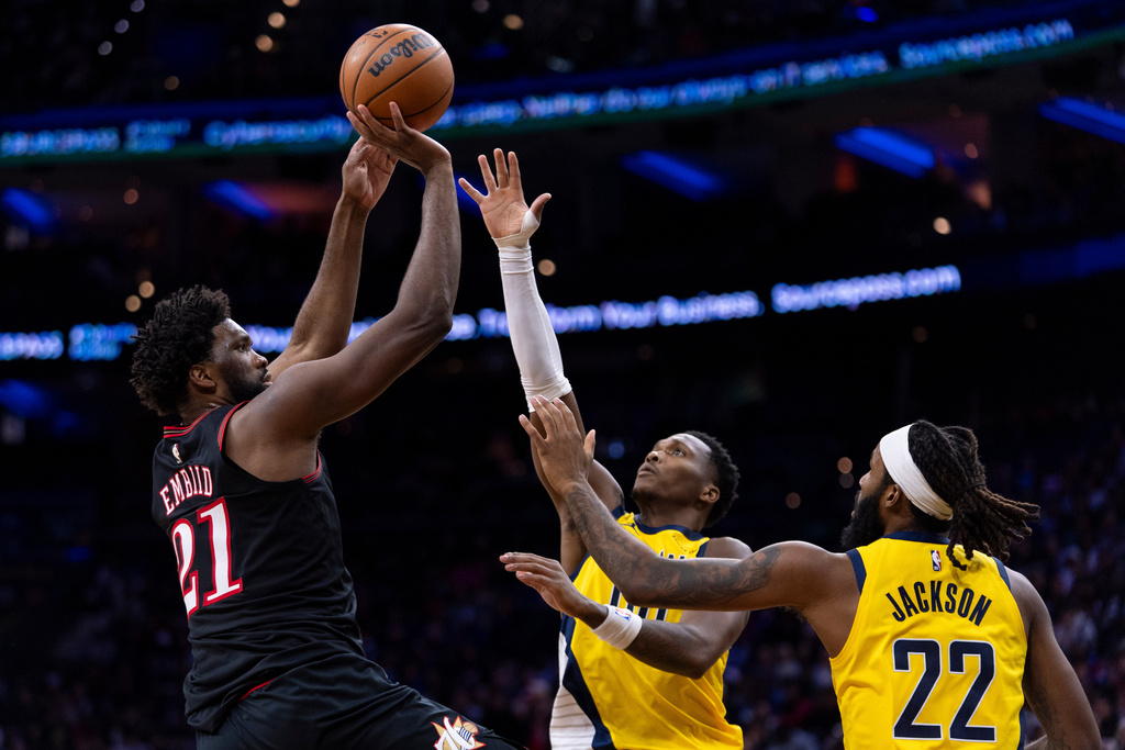 Philadelphia 76ers' Joel Embiid, left, looks to shoot against Indiana Pacers' Bennedict Mathurin, center, and Isaiah Jackson, right, during the first half of an NBA basketball game, Friday, Dec. 12, 2025, in Philadelphia. (AP Photo/Chris Szagola)