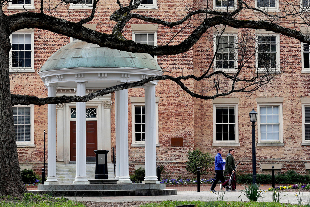 FILE - People walk through University of North Carolina campus March 18, 2020, in Chapel Hill, N.C. (AP Photo/Gerry Broome, File)