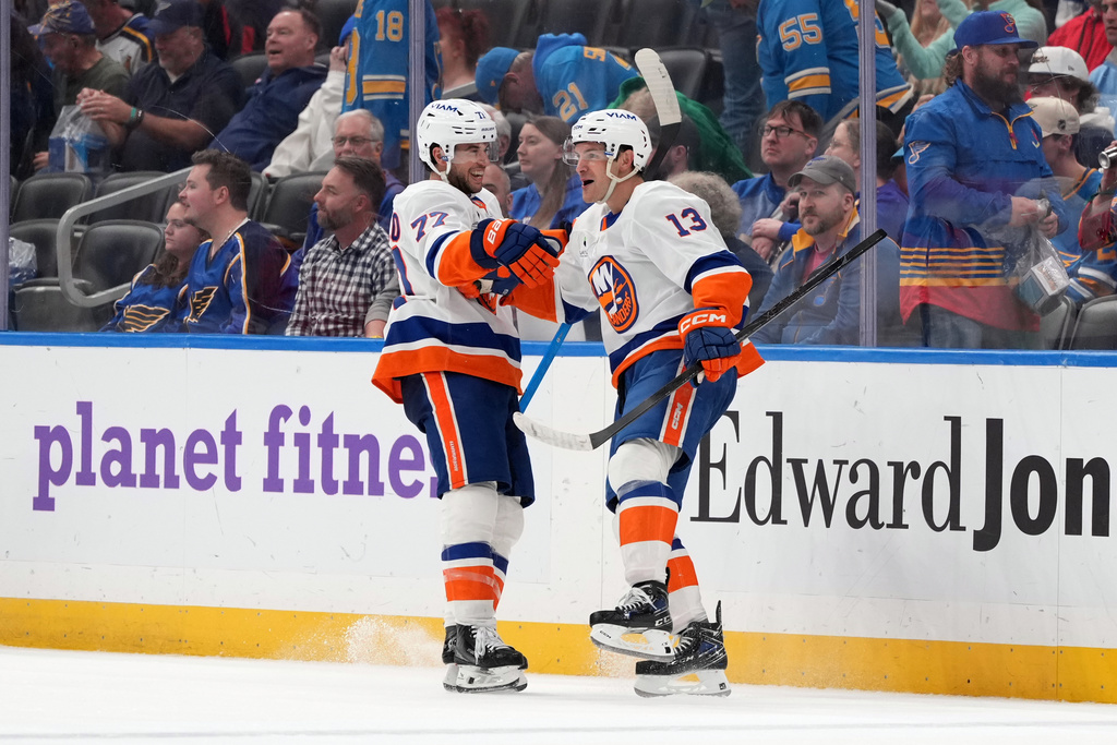 New York Islanders' Mathew Barzal (13) celebrates after scoring during overtime of an NHL hockey game to defeat the St. Louis Blues as teammate Tony DeAngelo (77) looks on Tuesday, March 10, 2026, in St. Louis. (AP Photo/Jeff Roberson)