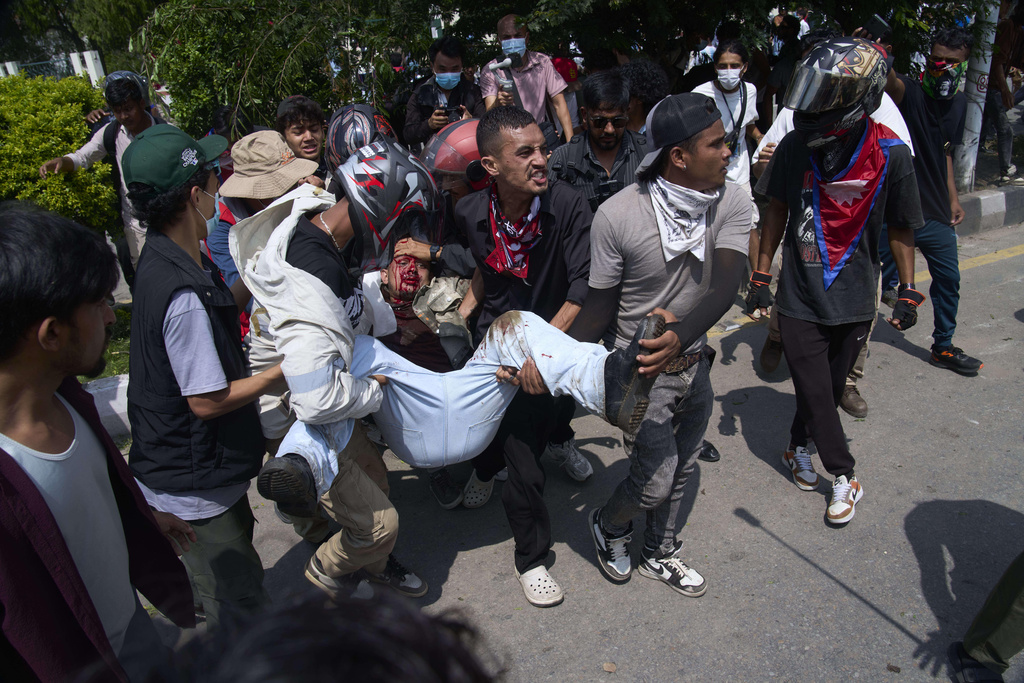 An injured protester is taken to hospital by his friends during a protest in front of the parliament building in Kathmandu, Nepal, Monday, Sept. 8, 2025. (AP Photo/Niranjan Shrestha)