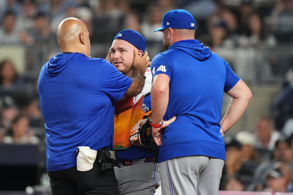 Toronto Blue Jays manager John Schneider, right, watches as a trainer checks on catcher Alejandro Kirk during the third inning of a baseball game against the New York Yankees Friday, Aug. 21, 2026, in New York. (AP Photo/Frank Franklin II)