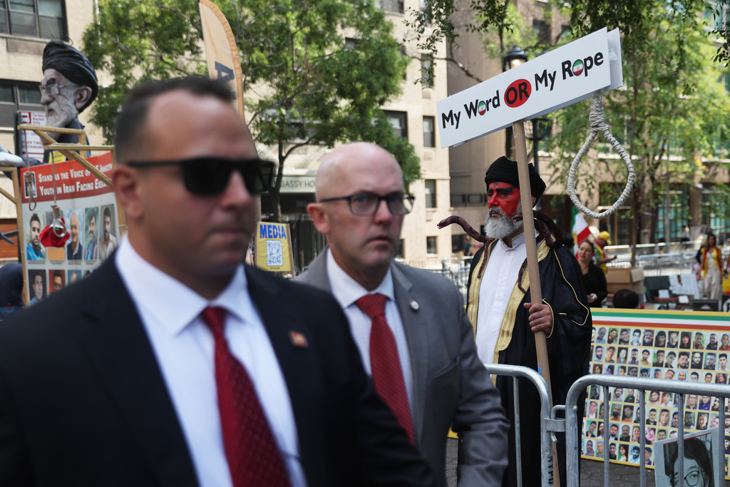 People walk past a rally against the Iranian government during the 80th session of the United Nations General Assembly, Tuesday, Sept. 23, 2025, in New York. (AP Photo/Heather Khalifa)