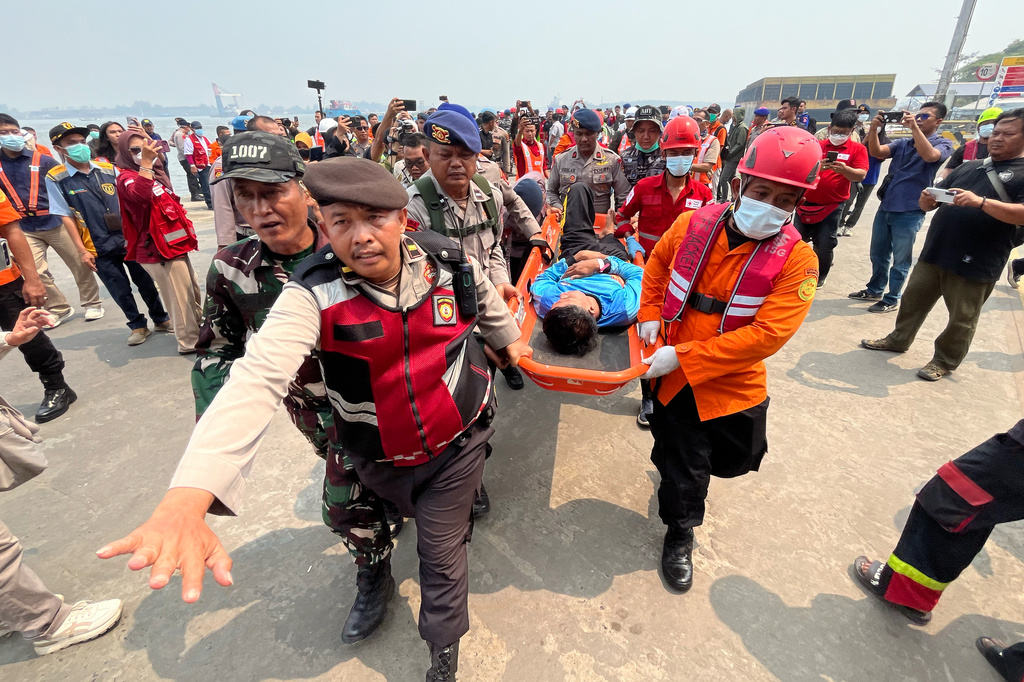In this photo taken with a smartphone, rescuers carry a survivor from a passenger ferry overturned in bad weather in the Java Sea on a stretcher upon arrival at a port in Banjarmasin, South Kalimantan, Indonesia, Tuesday, Sept. 15, 2026. (AP Photo/Iman Satria)
