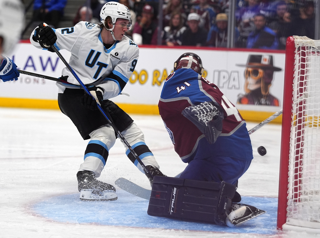 Utah Mammoth center Logan Cooley, left, shoots against Colorado Avalanche goaltender Scott Wedgewood (41) in the second period of an NHL hockey game Thursday, Oct. 9, 2025, in Denver. (AP Photo/David Zalubowski)