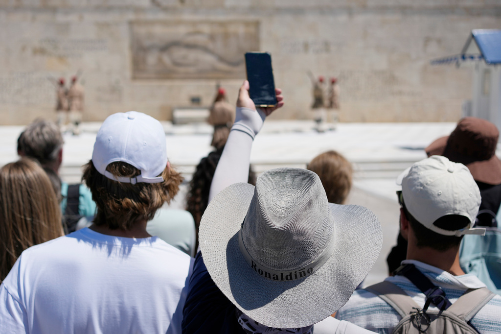 Tourists wearing hats visit the Tomb of the Unknown Soldier outside the Greek Parliament in Athens, Greece, Wednesday, Aug. 12, 2026. (AP Photo/Thanassis Stavrakis)