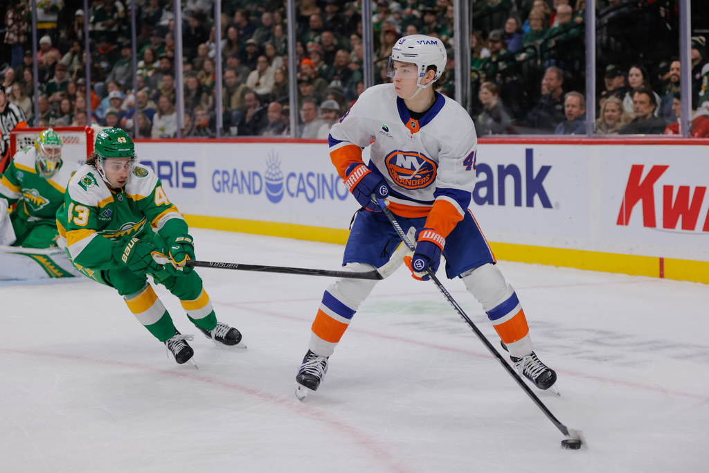 New York Islanders defenseman Matthew Schaefer (48) skates with the puck as Minnesota Wild defenseman Quinn Hughes (43) defends during the first period of an NHL hockey game Saturday, Jan. 10, 2026, in St. Paul, Minn. (AP Photo/Bailey Hillesheim)