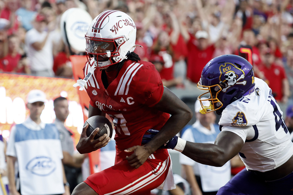 North Carolina State quarterback CJ Bailey, left, runs away from East Carolina's Julien Davis, right, for a touchdown during the first half of an NCAA college football game in Raleigh, N.C., Thursday, Aug. 28, 2025. (AP Photo/Karl DeBlaker)