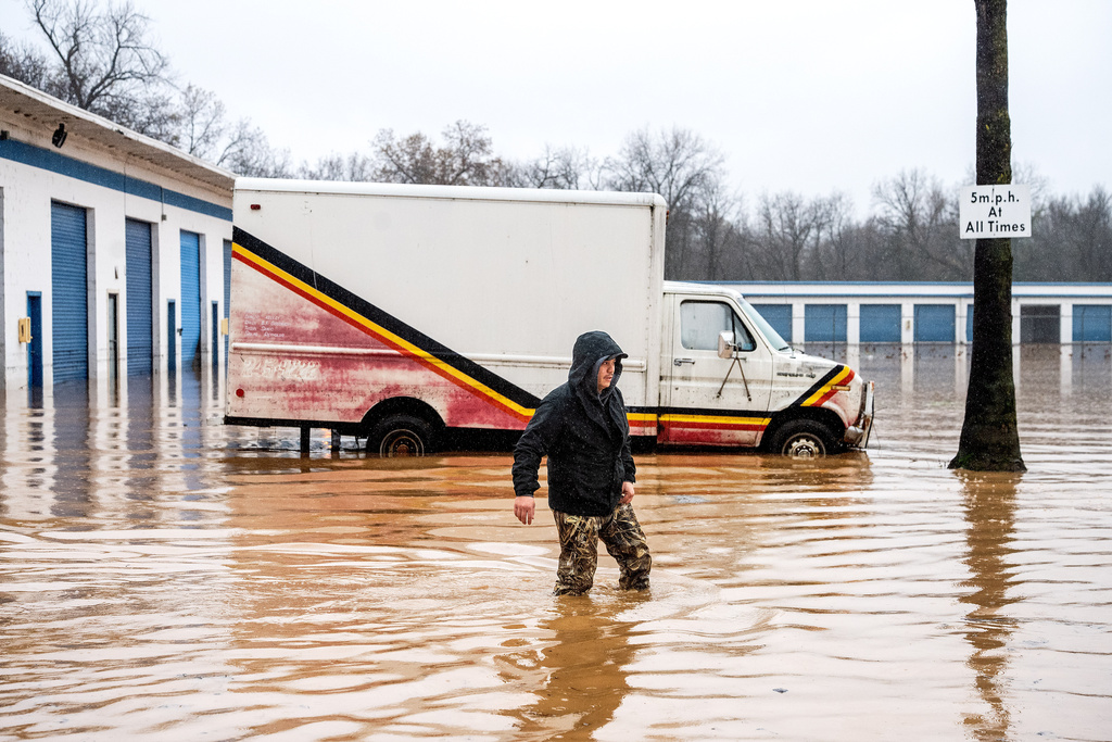Dekoda Cruz walks through flood water while helping a friend who's tire shop flooded during heavy rains on Monday, Dec. 22, 2025, in Redding, Calif. (AP Photo/Noah Berger)