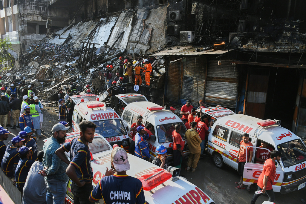 Ambulances are parked as rescue workers and firefighters work to search victims at the site of a burnt building of a multi-story shopping plaza following a massive fire in Karachi, Pakistan, Monday, Jan. 19, 2026. (AP Photo/Ali Raza)