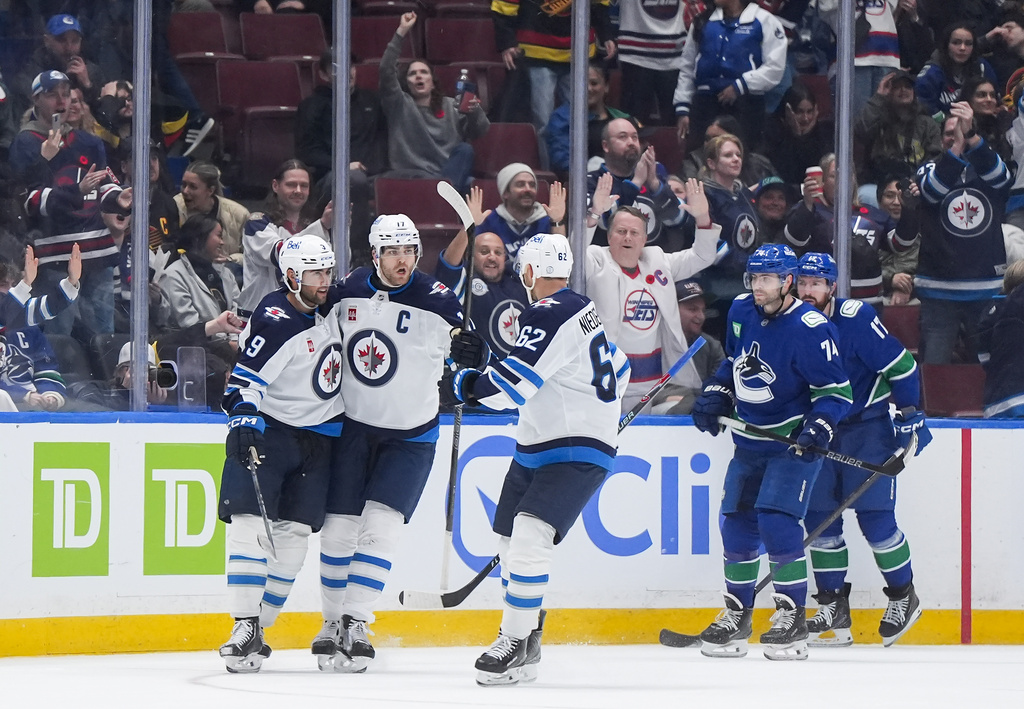 Winnipeg Jets' Alex Iafallo (9), Adam Lowry (17) and Nino Niederreiter (62) celebrate Iafallo's empty net goal as Vancouver Canucks' Jake DeBrusk (74) and Filip Hronek (17) look on during the third period of an NHL hockey game, in Vancouver, on Tuesday, Nov. 11, 2025. (Darryl Dyck/The Canadian Press via AP)