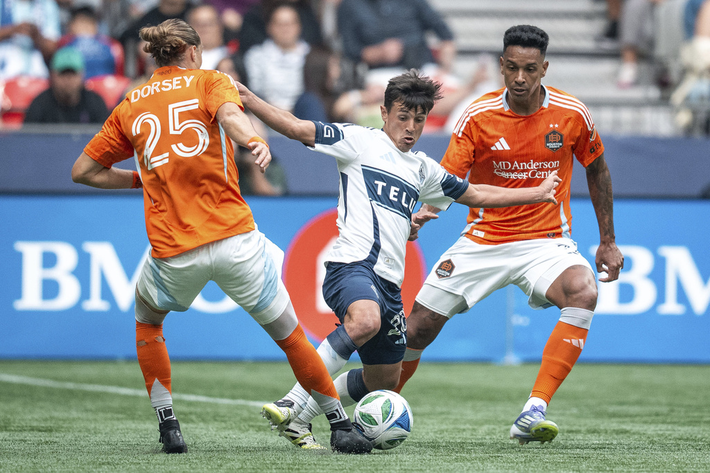 Vancouver Whitecaps' Andres Cubas, Houston Dynamo's Griffin Dorsey, and Antinio Carlos vie for the ball during the first half of an MLS soccer match in Vancouver, British Columbia, Sunday, Aug. 17, 2025. (Ethan Cairns/The Canadian Press via AP)