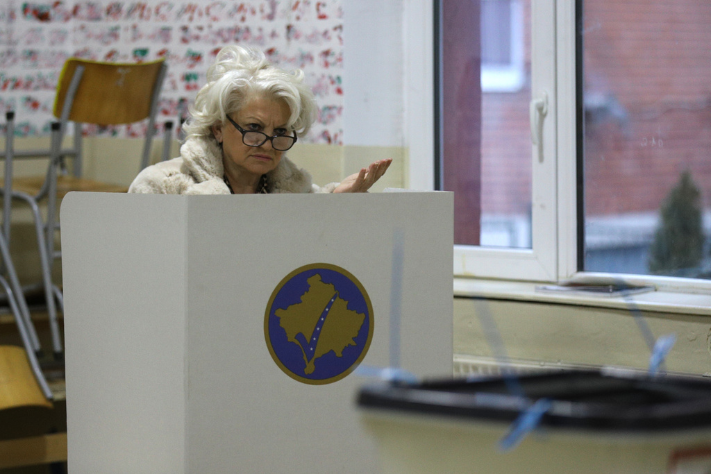 A voter prepares her ballot at a polling station in an early parliamentary election in the northern Serb-dominated part of ethnically divided town of Mitrovica, Kosovo, Sunday, Dec. 28, 2025. (AP Photo/Bojan Slavkovic)