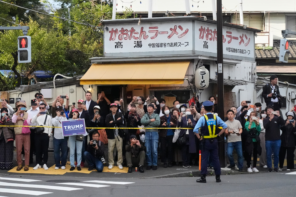 Bystanders look at a motorcade carrying President Donald Trump in Tokyo, Tuesday, Oct. 28, 2025, on his way to the USS George Washington, docked at a U.S. naval base in Yokosuka. (AP Photo/Mark Schiefelbein)