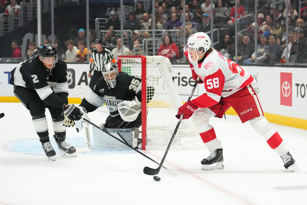 Detroit Red Wings center Emmitt Finnie, right, controls the puck as Los Angeles Kings defenseman Brian Dumoulin, left, and goaltender Darcy Kuemper defend during the first period of an NHL hockey game Thursday, Oct. 30, 2025, in Los Angeles. (AP Photo/Mark J. Terrill)