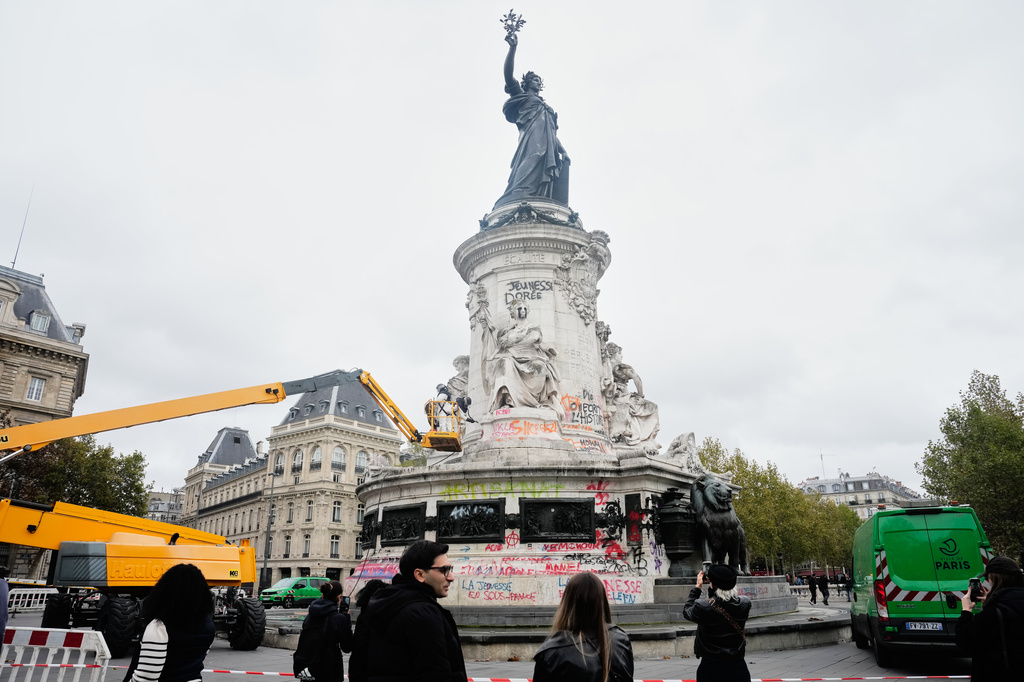 People watch and take photos of cleanup efforts after weekend protests over the cost of living turned into rioting and looting across France, in Paris, Wednesday, Oct. 21, 2026. (AP Photo/Teresa Suarez)