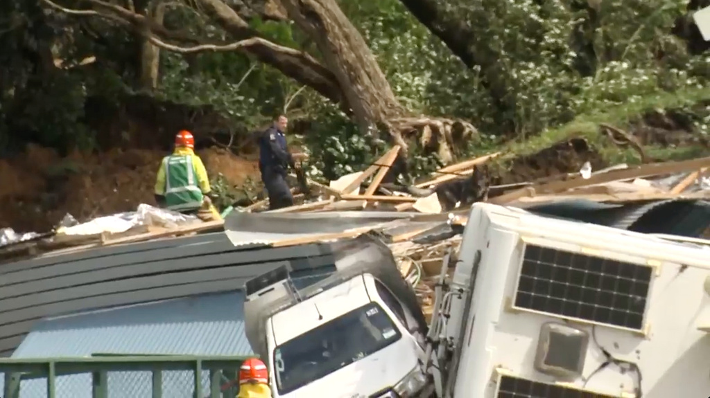 In this image from a video, a police officer with dog searches people near the site of a landslide at the base of Mount Maunganui on New Zealand’s North Island Thursday, Jan. 22, 2026. (TVNZ via AP)