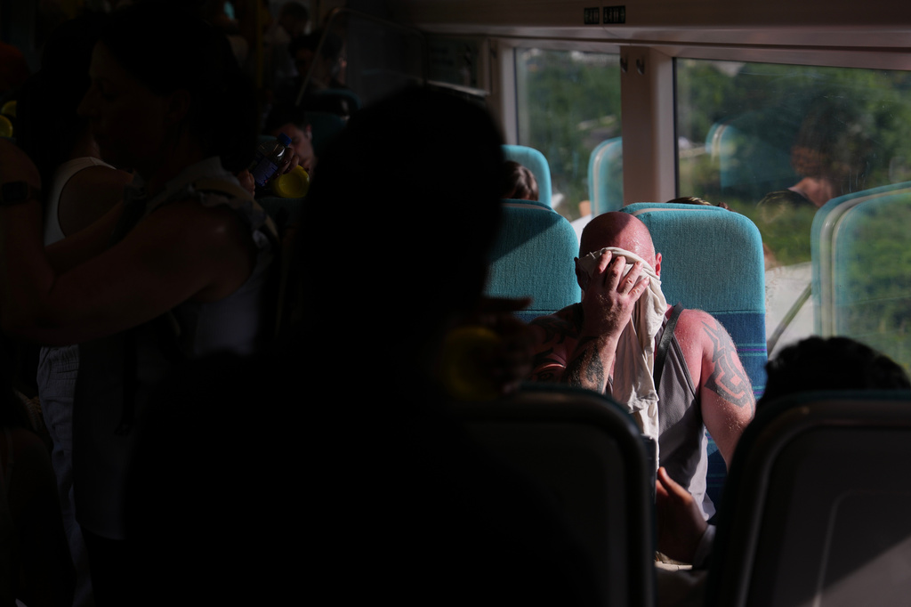 A man on a train wipes sweat from his face on a hot day in London, Wednesday, June 24, 2026. (AP Photo/Kin Cheung)