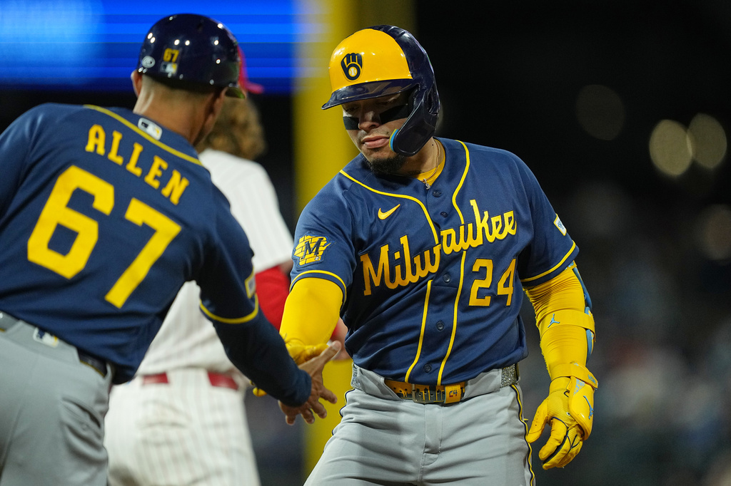 Milwaukee Brewers' William Contreras celebrates his hits a two-run single off of Philadelphia Phillies pitcher Aaron Nola with teammate first base coach Spencer Allen during the third inning of a baseball game, Wednesday, Sept. 23, 2026, in Philadelphia. (AP Photo/Matt Rourke)