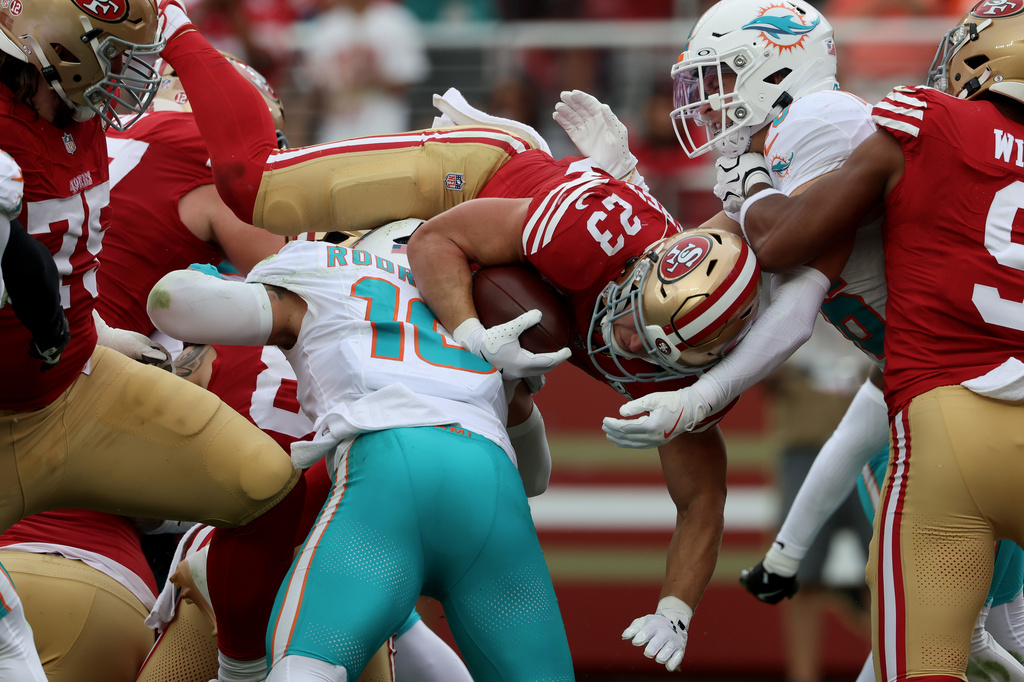 San Francisco 49ers running back Christian McCaffrey (23) jumps over Miami Dolphins linebacker Jacob Rodriguez (10) to score during the second half of an NFL football game in Santa Clara, Calif., Sunday, Sept. 20, 2026. (AP Photo/Jed Jacobsohn)