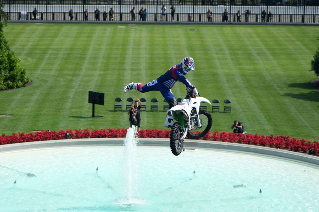 A motor sports athlete and stunt performer does a motorcycle jump ahead of the UFC Freedom 250 fights on the South Lawn of the White House, Saturday, June 13, 2026, in Washington. (AP Photo/Mark Schiefelbein, Pool)