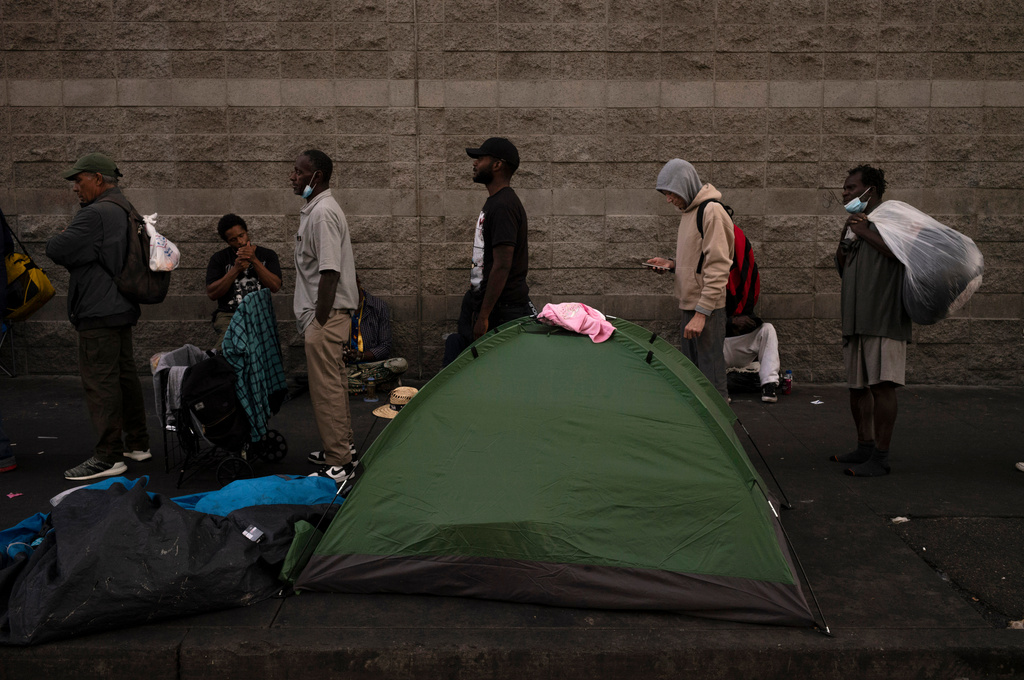FILE - Homeless people wait in line for dinner outside the Midnight Mission in the Skid Row area of Los Angeles, Oct. 25, 2023. (AP Photo/Jae C. Hong, File)