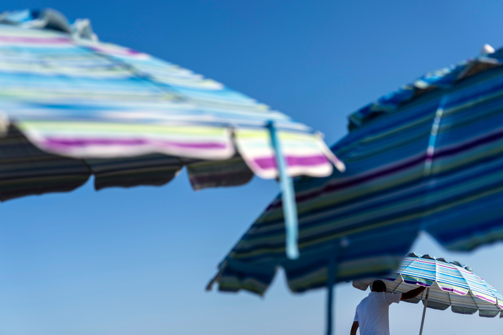 FILE - A resort worker folds up beach umbrellas Aug. 16, 2025, in South Yarmouth, Mass. (AP Photo/David Goldman, File)