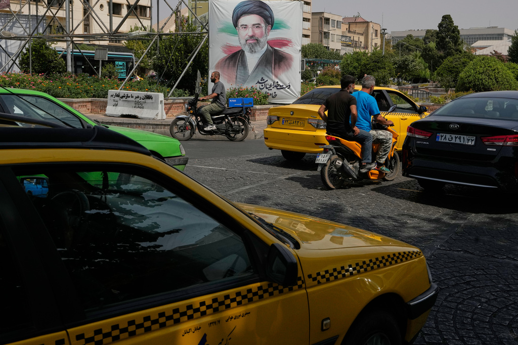 Vehicles pass a banner showing a portrait of the Iranian Supreme Leader Ayatollah Mojtaba Khamenei, in downtown Tehran, Iran, Monday, Aug. 31, 2026. (AP Photo/Vahid Salemi)