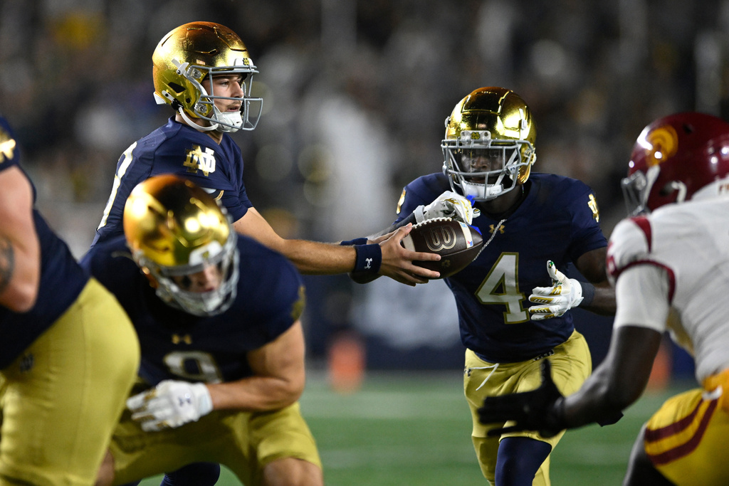 Notre Dame quarterback CJ Carr, left, hands off to running back Jeremiyah Love, right, before rushing for a touchdown during the first quarter of an NCAA college football game against Southern California, Saturday, Oct. 18, 2025, in South Bend, Ind. (AP Photo/Paul Beaty)