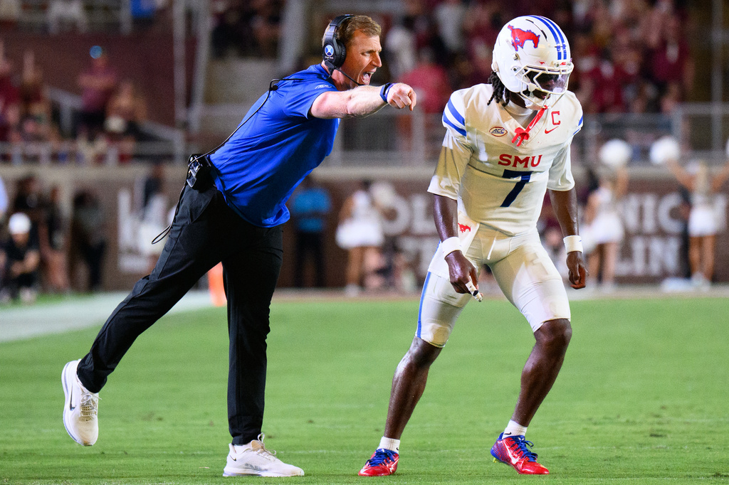 SMU head coach Rhett Lashlee, left, talks to quarterback Kevin Jennings (7) between plays during the first half of an NCAA college football game against Florida State, Monday, Sept. 7, 2026, in Tallahassee, Fla. (AP Photo/Noah Lantor)