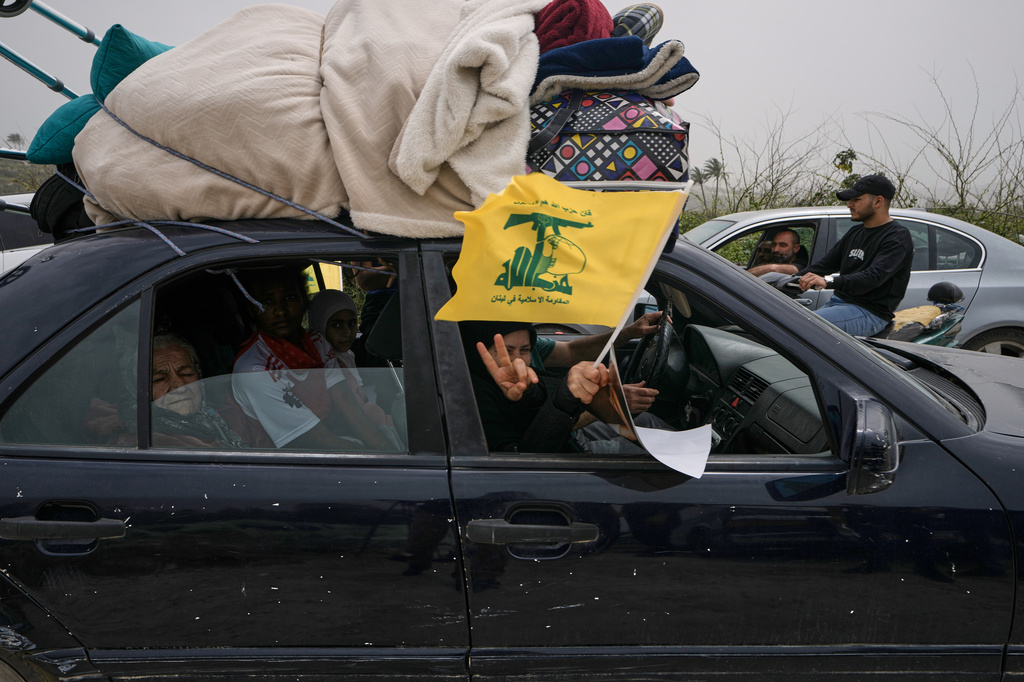 A displaced woman waves a Hezbollah flag, as she returns with her family to their village on the second day of a ceasefire between Hezbollah and Israel in Qasmiyeh, near Tyre city, southern Lebanon, Saturday, April 18, 2026. (AP Photo/Bilal Hussein)