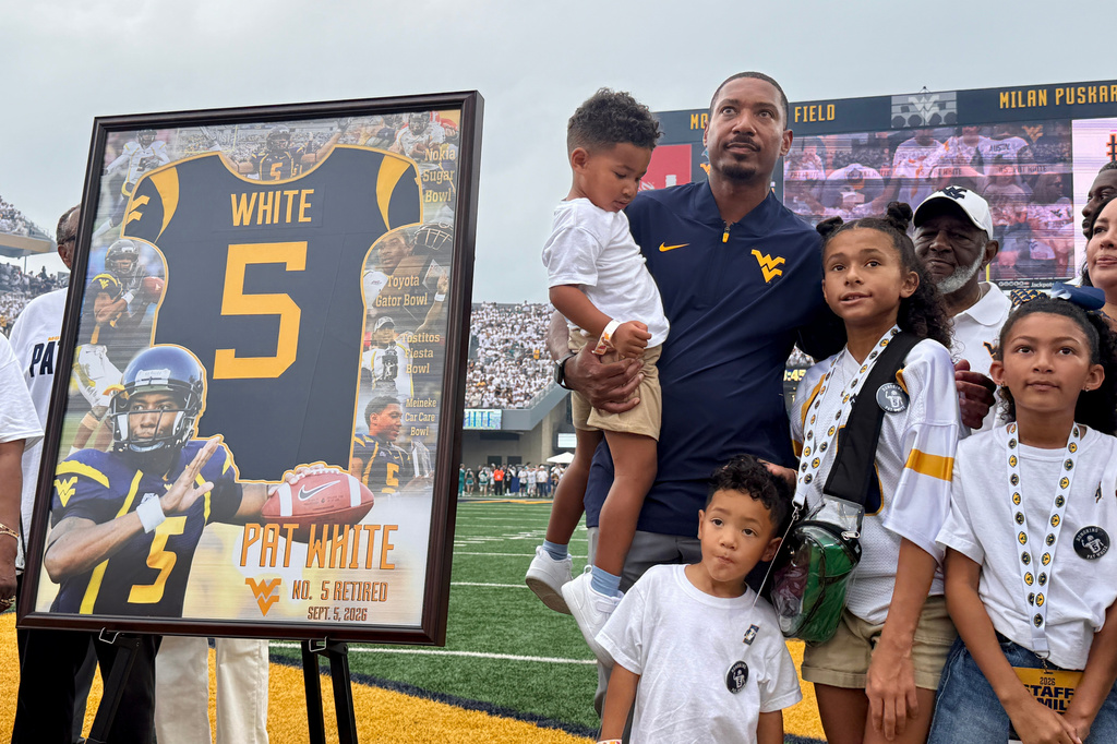 Former West Virginia quarterback and current Mountaineer assistant coach Pat White stands with his family during a ceremony to retire his No. 5 number, Saturday, Sept. 5, 2026, prior to kickoff at West Virginia's home NCAA college football game against Coastal Carolina in Morgantown, W.Va. (AP Photo/John Raby)