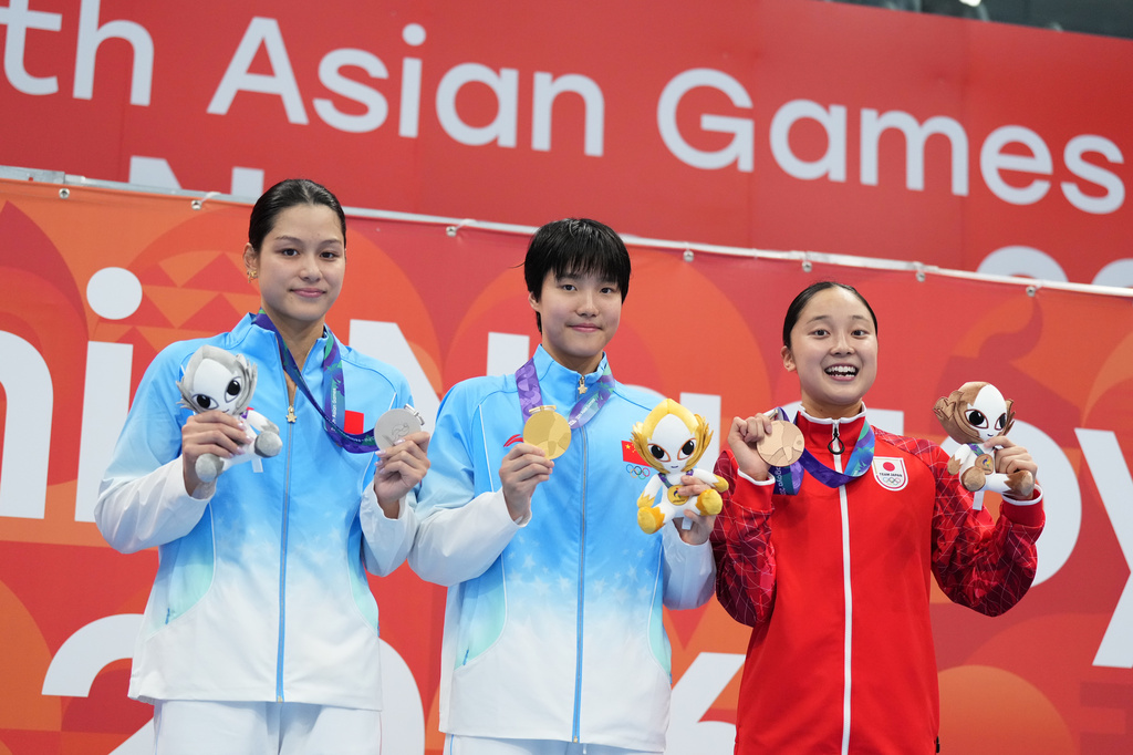 Gold medalist Yu Zidi of China, center, flanked by silver medalist Yu Yiting of China, left, and bronze medalist Mio Narita of Japan pose on the podium after the women's 200-meter individual medley final in swimming at the Asian Games in Tokyo, Japan, Monday, Sept. 21, 2026. (AP Photo/Hiro Komae)