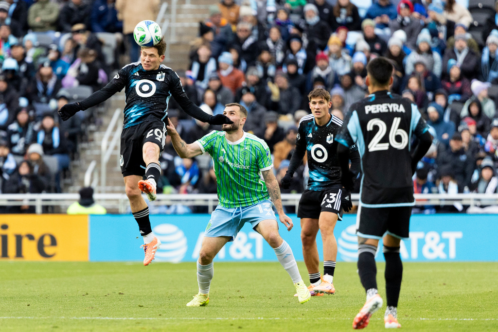 Minnesota United midfielder Will Trapp, left, goes up for a header against Seattle Sounders forward Jordan Morris (13) during the first half of Game 3 in the first round of MLS soccer's Western Conference playoffs in St. Paul, Minn., Saturday, Nov. 8, 2025. (AP Photo/Ellen Schmidt)