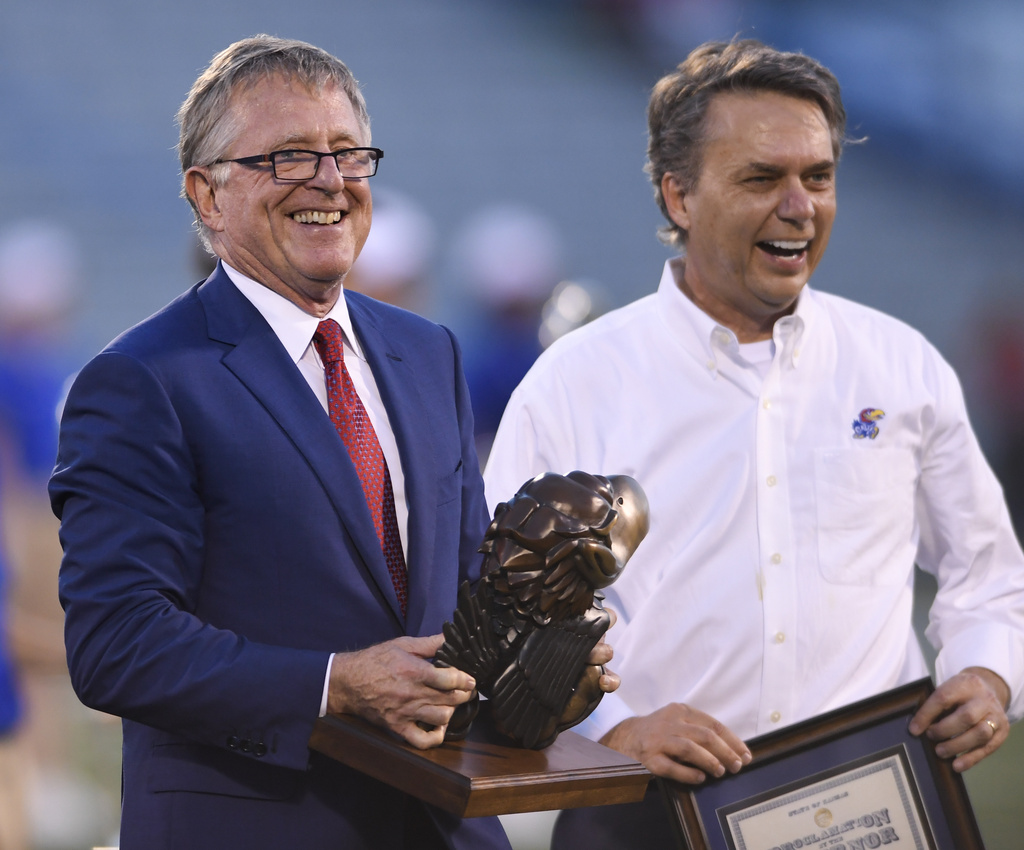 FILE - David Booth, left, receives a proclamation from then-Kansas Gov. Jeff Colyer, M.D., during halftime of a Kansas NCAA college football game in Lawrence, Kan., Sept. 1, 2018. (AP Photo/Reed Hoffmann, file)
