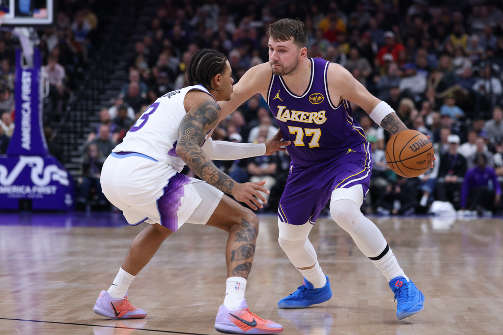 Los Angeles Lakers guard Luka Doncic (77) moves the ball against Utah Jazz guard Keyonte George (3) during the first half of an NBA basketball game Thursday, Dec. 18, 2025, in Salt Lake City. (AP Photo/Rob Gray)