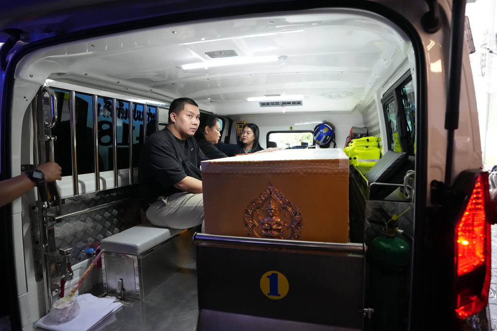 A relative sits near a coffin containing the body of a victim of Friday's shooting at the Debsirin Nonthaburi School, inside an ambulance at a police hospital in Bangkok,Thailand, Saturday, Aug. 8, 2026. (AP Photo/Sakchai Lalit)