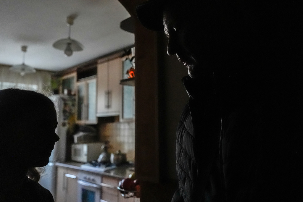 Oleksandr Leheda, who picks up odd jobs outside of his work as a power line repairman for Chernihiv Oblenergo, to make ends meet, greets his daughter in the family's apartment where a blackout was caused by Russian attacks, Friday, Oct. 17, 2025, in Chernihiv, Ukraine. (AP Photo/Julia Demaree Nikhinson)