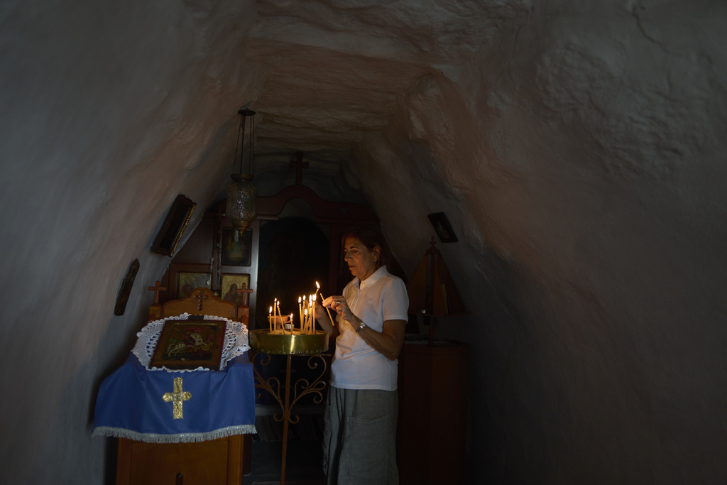 Dragana Grozdanovic, whose son was married in a family chapel in Tinos, lights a candle in Agios Giorgos (St. George), a 200-year-old chapel near the village of Volax on Tinos island, Greece, Thursday, Sept. 4, 2025. (AP Photo/Petros Giannakouris)