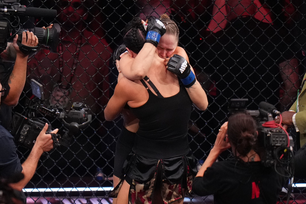 Ronda Rousey, of the United States, behind, hugs Gina Carano, of the United States, after Rousey defeated Carano in their featherweight mixed martial arts fight Saturday, May 16, 2026, in Inglewood, Calif. (AP Photo/Jae C. Hong )