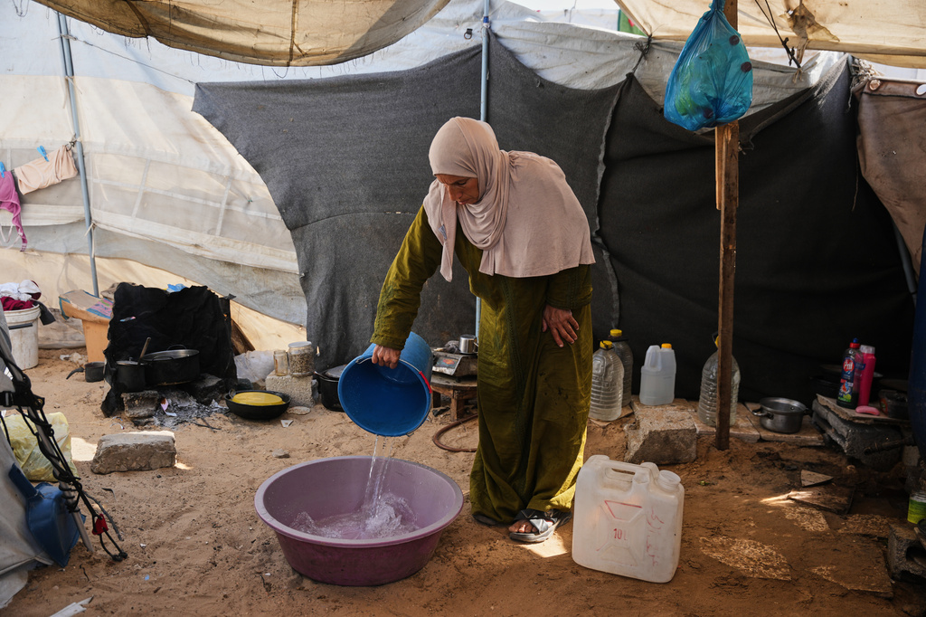 Displaced Palestinian Reem Abu Lahia uses water to do laundry inside the tent where she lives in Khan Younis, in the southern Gaza Strip, Thursday, April 30, 2026. (AP Photo/Abdel Kareem Hana)
