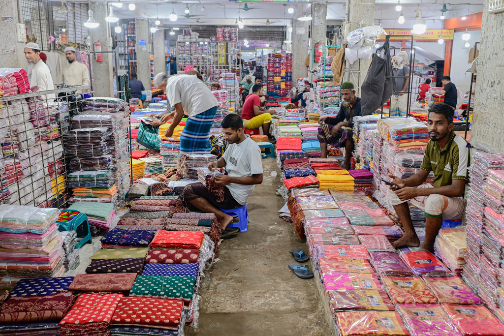 Shopkeepers arrange saris at a weekly wholesale market in Tangail District, Bangladesh, Nov. 5, 2025. (AP Photo/Mahmud Hossain Opu)