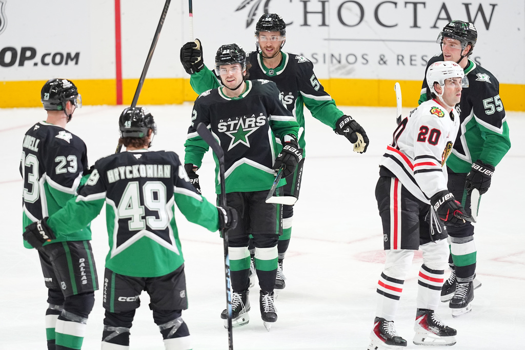 Dallas Stars center Justin Hryckowian (49) celebrates his third period goal with teammates as Chicago Blackhawks center Ryan Greene (20) skates by during an NHL hockey game Sunday, March 8, 2026, in Dallas. (AP Photo/Julio Cortez)