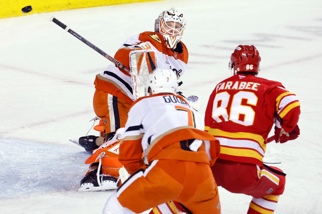 Anaheim Ducks goalie Ville Husso, top, makes a save as Calgary Flames' Joel Farabee (86) and Ducks' Radko Gudas watch the puck during the first period of an NHL hockey game in Calgary, Alberta, Thursday, March 26, 2026. (Larry MacDougal/The Canadian Press via AP)