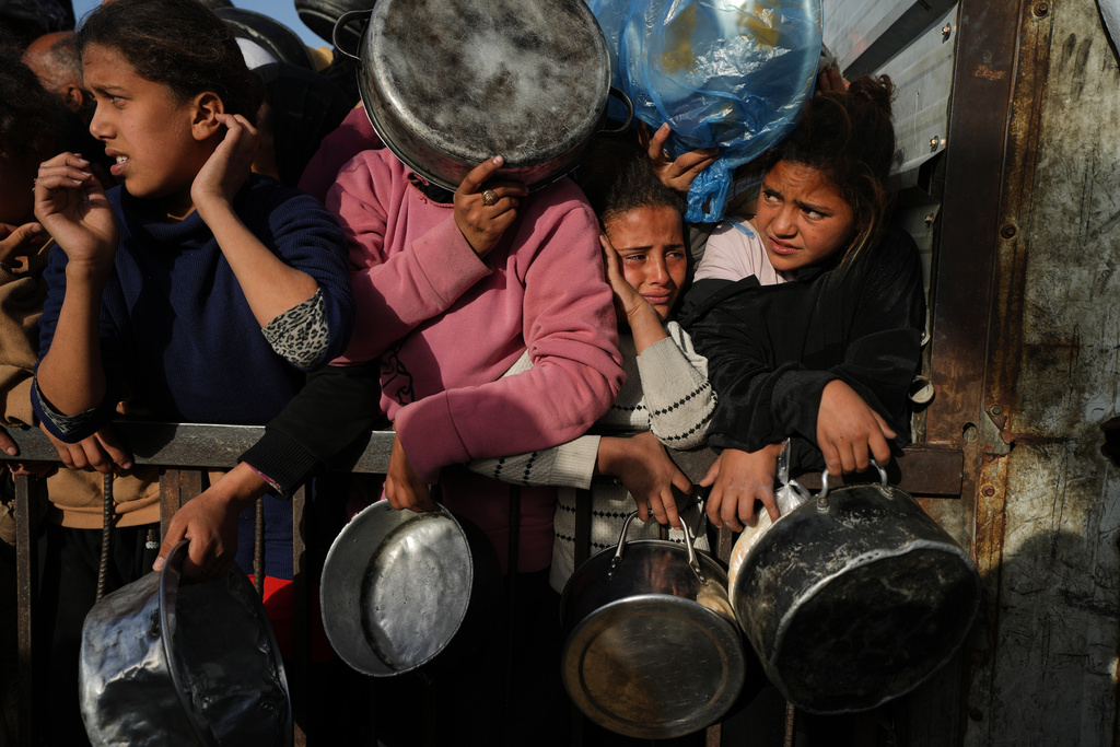 Displaced Palestinian struggle to receive donated food for iftar, the fast-breaking meal, on the first day of the Muslim holy month of Ramadan at a community kitchen in Khan Younis, Gaza Strip, Wednesday, Feb. 18, 2026. (AP Photo/Jehad Alshrafi)