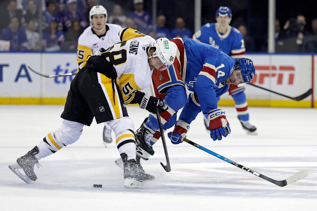 Pittsburgh Penguins defenseman Kris Letang (58) checks New York Rangers right wing Taylor Raddysh (14) off the puck in the second period of an NHL hockey game Tuesday, Oct. 7, 2025, in New York. (AP Photo/Adam Hunger)