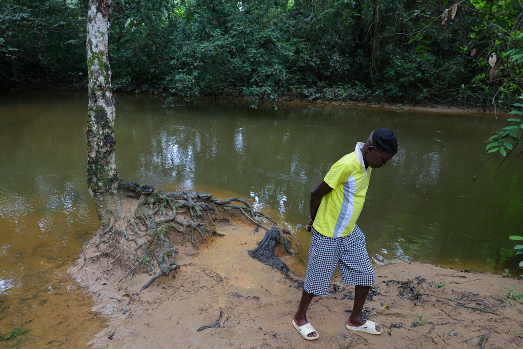 Mustapha Pabai, the town chief, walks beside a polluted river, in Jikando, Liberia, July 8, 2025. (AP Photo/Misper Apawu)